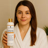 Woman in white robe holding The Essentials Almond Honey Bliss Conditioner – ideal for hair care routine